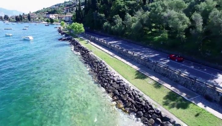 Fiat 124 Spider, vista dall'alto su strada che costeggia un lago.
