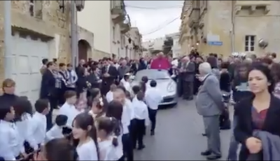 Arcivescovo saluta i fedeli da una Porsche trainata da 50 bambini